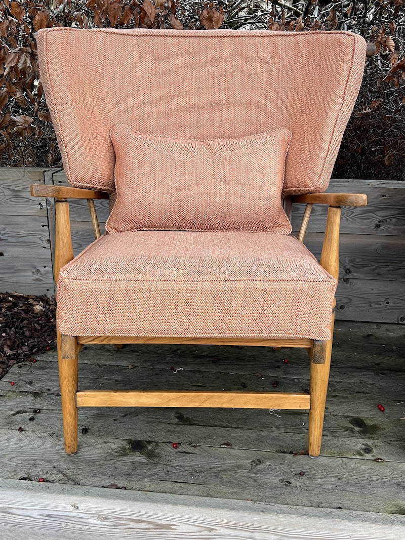 Elegant wooden armchair featuring a plush orange fabric cushion and a stylish backrest, perfect for any living space.