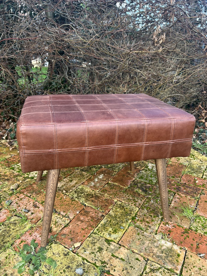 Stylish reclaimed leather footstool with a quilted design and wooden legs, perfect for any modern living space.