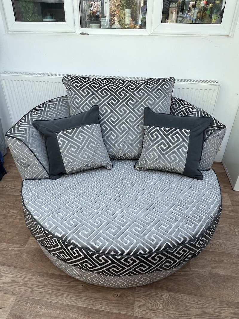 Stylish CUDDLE CHAIR featuring a round design, plush cushions, and a modern geometric pattern for ultimate comfort and elegance.