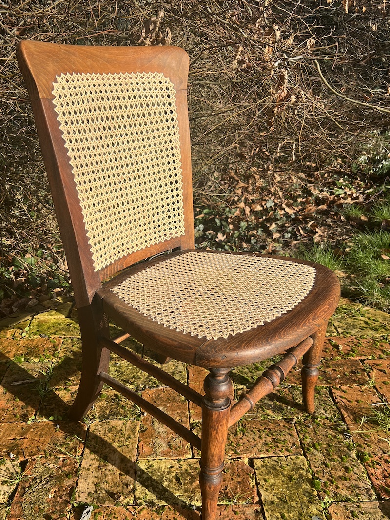 Handcrafted vintage chair featuring a woven cane seat and backrest, showcasing elegant woodwork and timeless design.