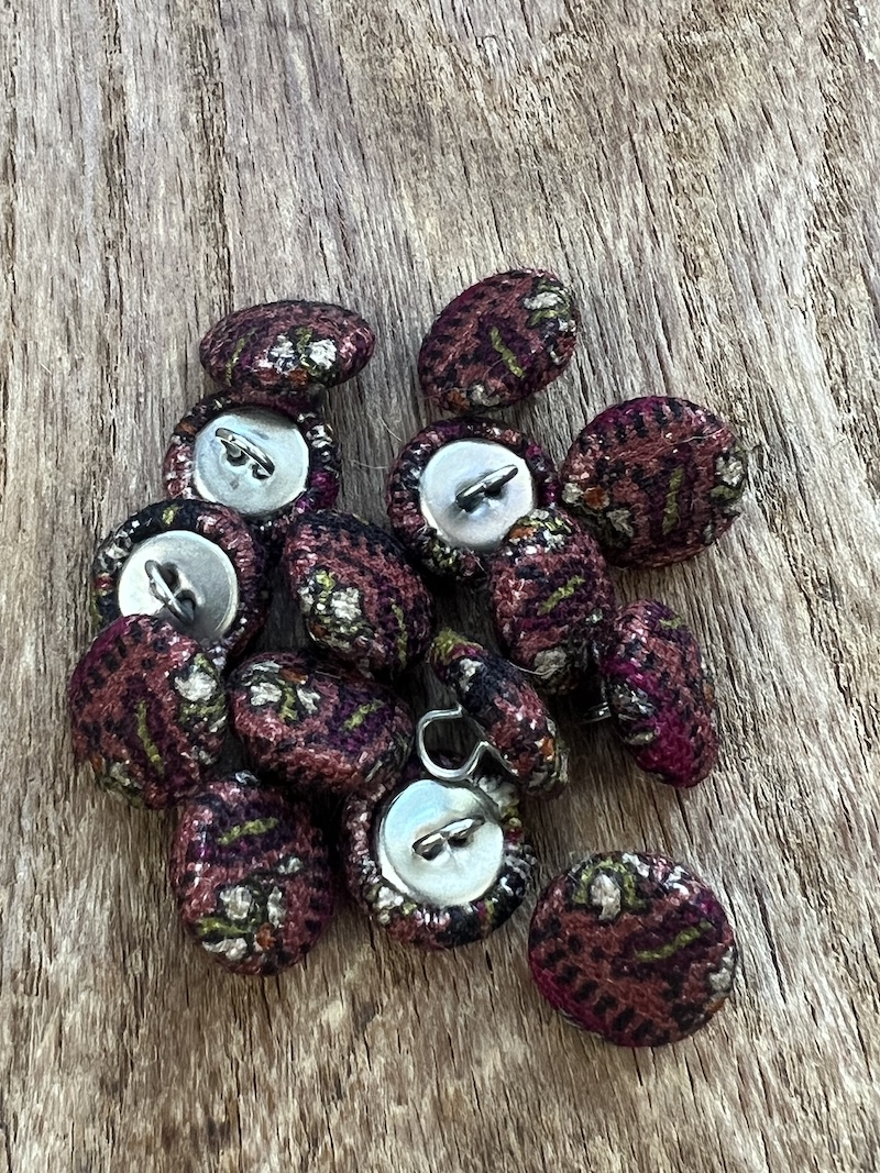 A charming set of warm pink buttons featuring intricate patterns, perfect for adding a unique touch to your sewing projects.