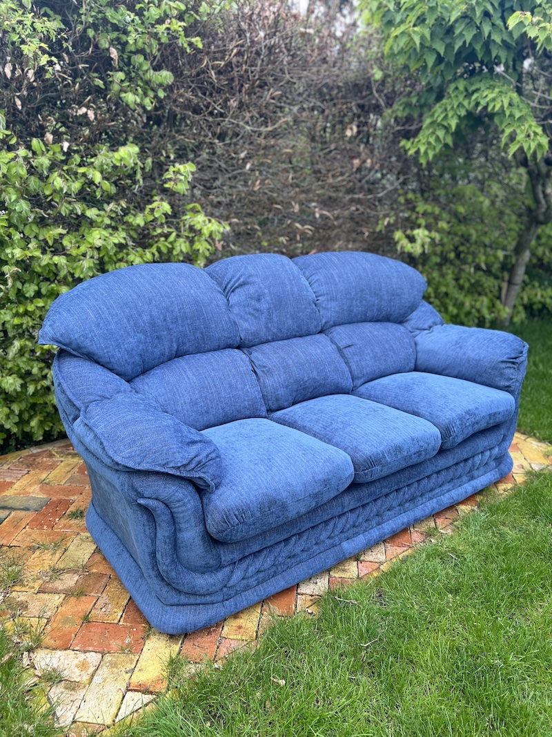 Cozy blue sofa featuring plush cushions, perfect for outdoor relaxation and stylish seating in any setting.