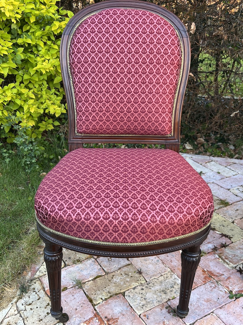Elegant Louis XVI style dining chair featuring rich red upholstery and intricately carved wooden legs. Perfect for timeless decor.