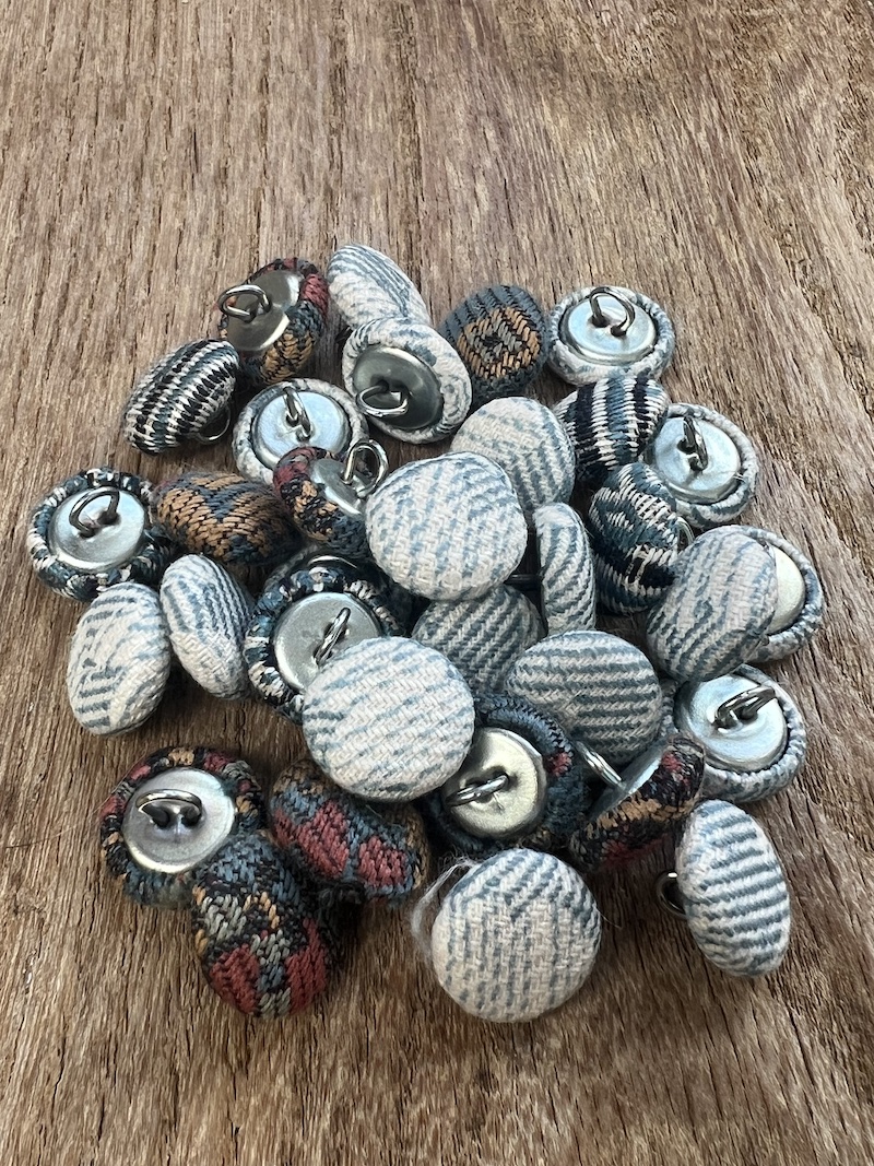 A variety of fabric-covered buttons in heritage blue tones, perfect for adding a unique touch to your projects.