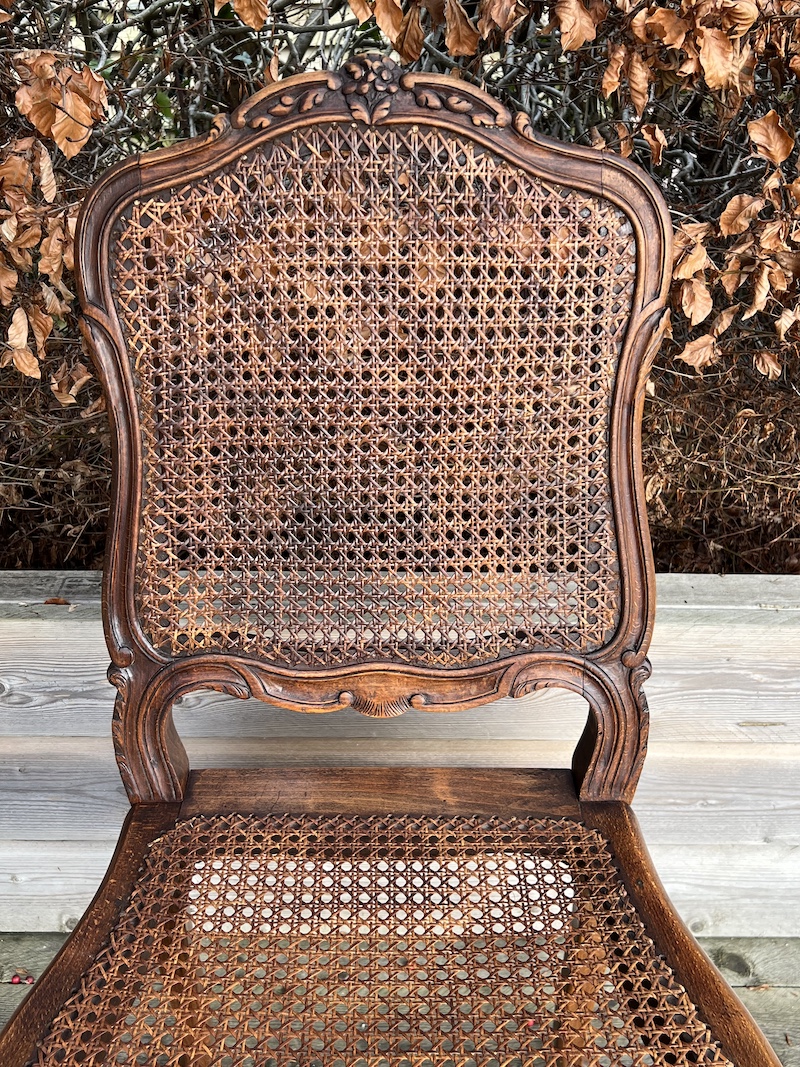 Elegant French cane dining chair featuring intricate woodwork and a classic design, perfect for any dining space.