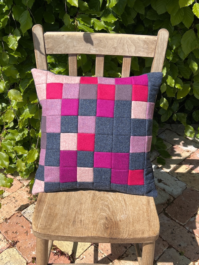 Add a pop of color to your space with the PIXELATED CUSHION in pink, featuring a stylish patchwork design.
