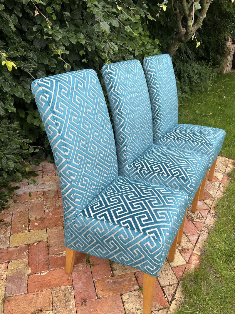 Stylish modern dining chairs featuring a vibrant geometric pattern on soft upholstery, complemented by sturdy wooden legs.